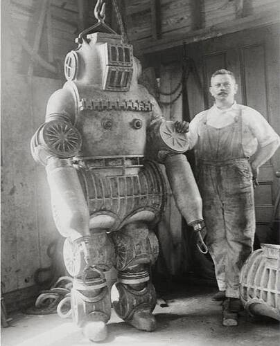 Inventor Chester E. MacDuffee stands next to one of the first atmospheric diving suits, circa 1911. The suit weighed 550 pounds