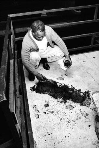 Theatrice Bailey, the brother of the owner of the Lorraine Motel in Memphis, Tennessee, scrapes blood from the balcony following Martin Luther King Jr.'s assassination