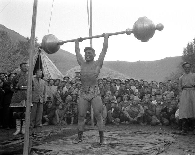 Man lifting weights in front of an audience. Mongolia, 1956
