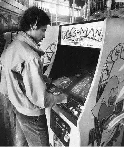 Man listening to his Walkman while playing Pac-Man, the ultimate 1980s experience in one photo.