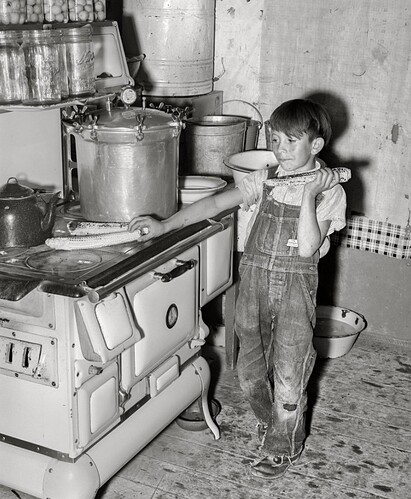A young boy finds happiness in the rich flavor of sweet corn roasted over a hot stove. Chamisal, New Mexico. (1940)