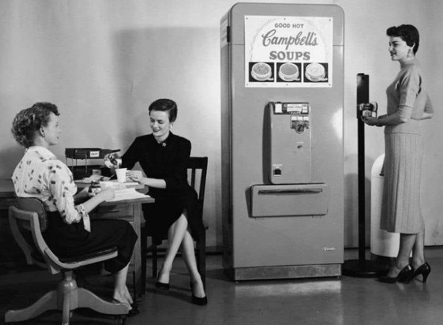 Office staff enjoying soup from a Campbell’s Soup vending machine. (1950s)